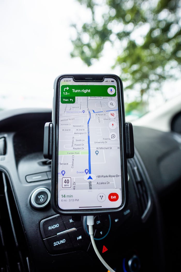 Close-up of a smartphone with GPS navigation app mounted on car dashboard.